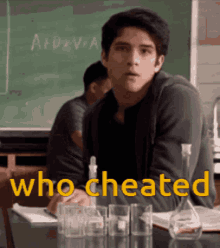 a young man sits at a desk in front of a blackboard with the words who cheated written on it