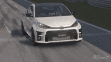 a white toyota yaris is driving on a track