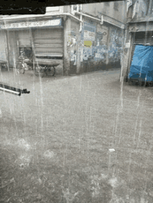 rain is falling on a flooded street in front of a store that has a sign that says ' shree ram '