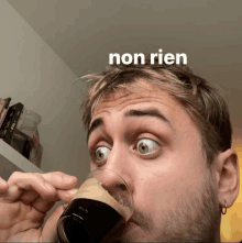 a man drinking from a glass with the word non rien on the bottom