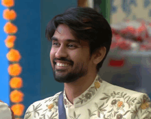 a man with a beard wearing a floral shirt smiles