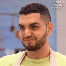 a man with a beard is smiling in front of a sign that says " the great canadian baking show "