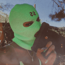 a woman wearing a green ski mask has the number 22 on her face