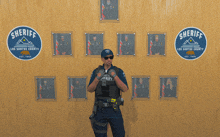 a man in a sheriff uniform stands in front of a wall with pictures of sheriffs from los santos county