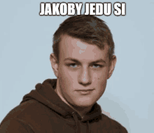 a young man wearing a brown hoodie with jakoby jedu si written on the bottom