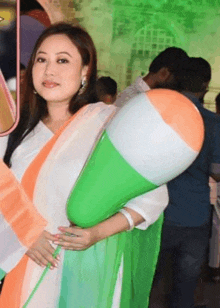 a woman in a white dress is holding a balloon in the shape of an indian flag .