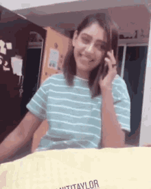 a woman wearing a striped shirt is smiling while talking on a cell phone