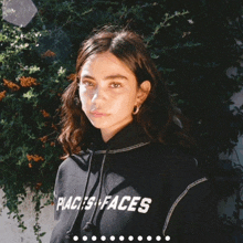 a woman wearing a black hoodie that says ' places faces ' on it