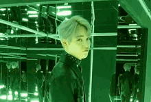 a young man is standing in a room with a lot of mirrors and lights .