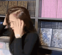 a woman covering her ears in front of a shelf of books including one that says ' asimov ' on it