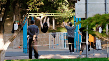 a man is hanging upside down on a bar while another man watches