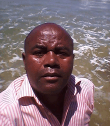 a man in a striped shirt is standing in the water looking at the camera