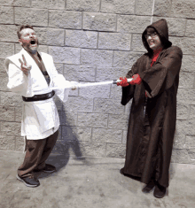 a man in a white robe is holding a light saber and a woman in a brown robe is holding a red light saber