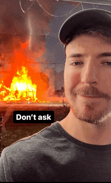 a man stands in front of a burning house and says " don 't ask " on the bottom