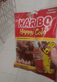 a person holding a bag of haribo happy cola