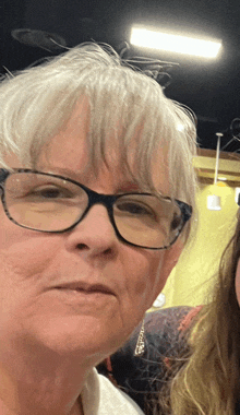 a close up of a woman wearing glasses looking at the camera