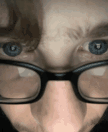 a close up of a person 's face with glasses and blue eyes