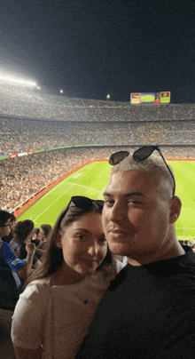 a man and a woman are posing for a picture in a stadium