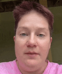 a close up of a woman 's face with a pink shirt on