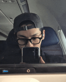 a man wearing glasses and a hat takes a selfie