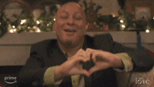 a man and woman are making a heart shape with their hands in front of a sign that says " with love "