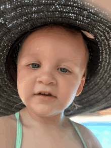 a little girl wearing a black hat looks at the camera with a serious look on her face