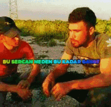 a man in a red shirt sits next to a man in a green shirt with the words " bu sercan neden bu kadar gavit "