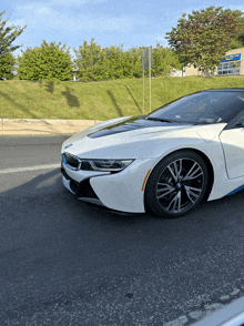 a white bmw i8 is parked on the side of a road