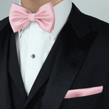 a man in a tuxedo with a pink bow tie and a pink pocket square