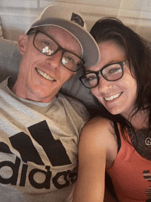 a man wearing an adidas shirt and a woman wearing glasses