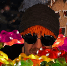 a man wearing sunglasses and a beanie is surrounded by candy