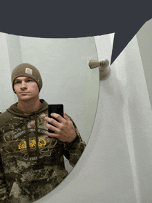 a man taking a picture of himself in a mirror with a carhartt hat on