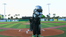 a person in a storm trooper costume stands on a baseball field in front of a sign that says holiday inn resort