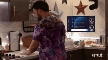 a man in a purple tie dye shirt is standing in a kitchen with a netflix sign on the counter