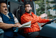 a man in a red shirt is talking to another man in a bus