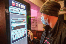 a man wearing a mask is looking at a screen that says " categories "