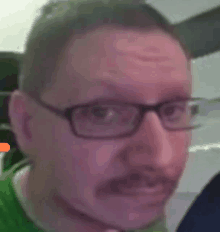 a man wearing glasses and a green shirt is making a funny face