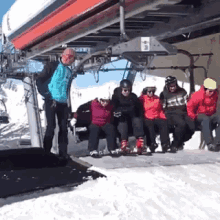 a group of people are sitting on a ski lift with a sign that says ' a ' on it