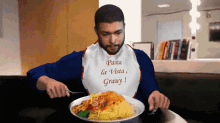 a man wearing a bib that says pasta la vista gravy is eating spaghetti