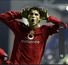 a soccer player wearing a red vodafone jersey is making a funny face