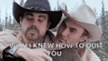 two men in cowboy hats are standing next to each other and talking .