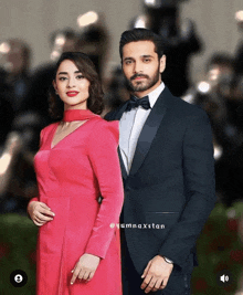 a man in a tuxedo and a woman in a red dress pose for a picture