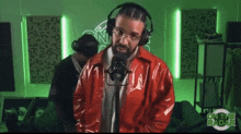 a man in a red jacket is sitting in front of a microphone with on the radar in the background