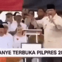 a man is standing in front of a crowd with a sign that says ' anye terbuka pilpres ' on it