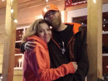 a man wearing an orange hat with the word eagles on it hugs a woman