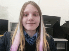 a girl with pink and white hair is smiling in front of an intel computer monitor