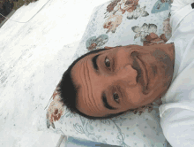 a man laying on a floral pillow making a face