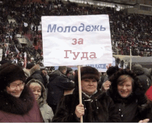 a woman holds up a sign that says " молодеж "