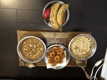 a wooden tray with bowls of food and a bowl of bananas on top