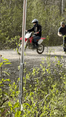 a man riding a dirt bike down a dirt road